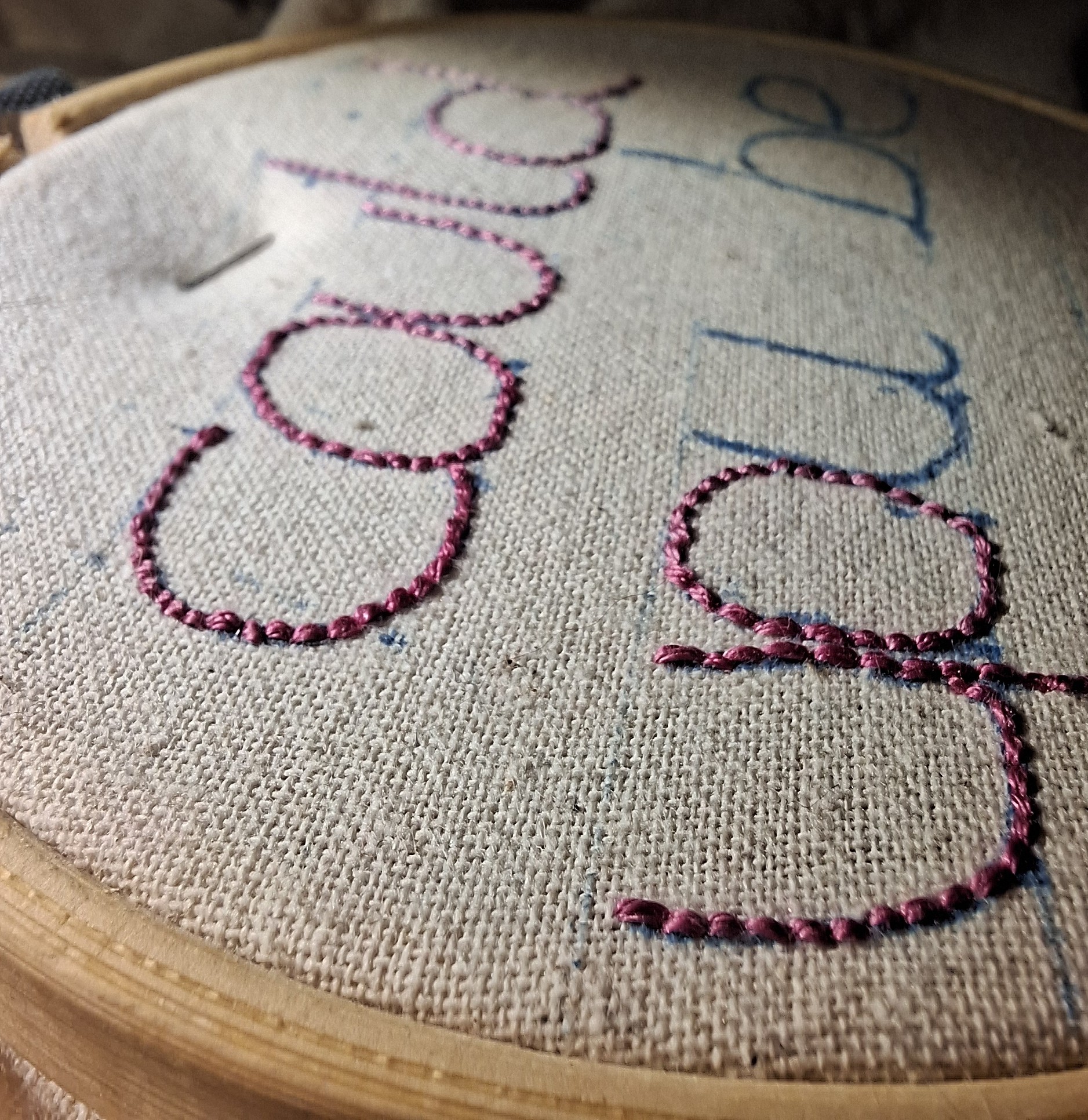 Photo très rapprochée d'un tissus tendu sur un tambour de broderie. Il est brodé "could you be" en rose Photo très rapprochée d'un tissus tendu sur un tambour de broderie. Il est brodé "could you be" en rose