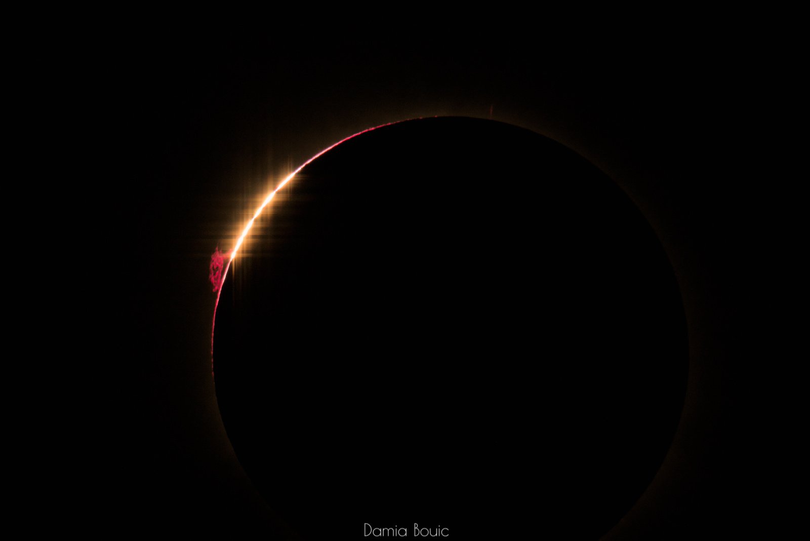 La Lune occulte presque totalement le Soleil. Quelques ultimes grains de lumière s'éteignent sur le limbe lunaire, comme une chapelet. Juste en dessous, une protubérance d'un rouge vif, déchiquetée, se présente. La Lune occulte presque totalement le Soleil. Quelques ultimes grains de lumière s'éteignent sur le limbe lunaire, comme une chapelet. Juste en dessous, une protubérance d'un rouge vif, déchiquetée, se présente.
