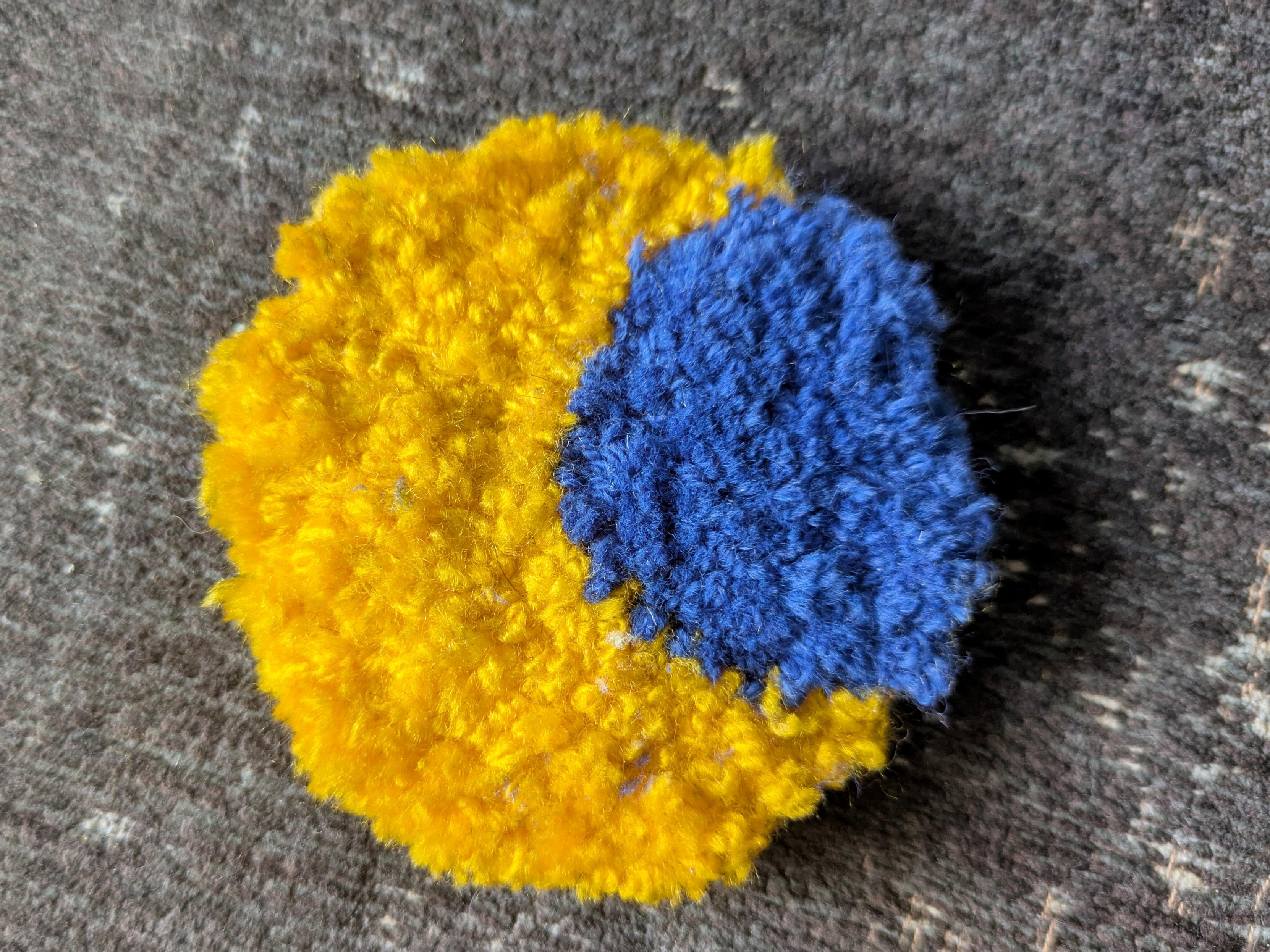 Photo d'un mini tapis au punch needle : un rond avec un croissant de lune jaune, et du bleu foncé dans le trou Photo d'un mini tapis au punch needle : un rond avec un croissant de lune jaune, et du bleu foncé dans le trou