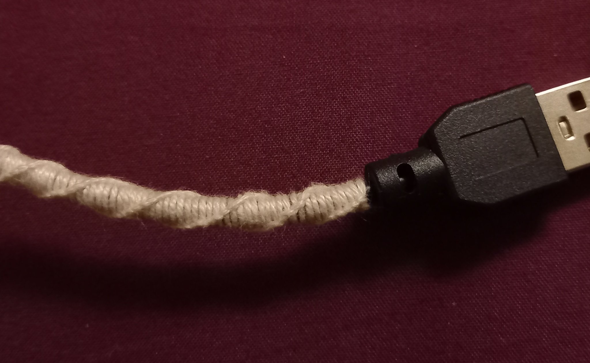 Un câble USB protégé par une torsade à deux brins de coton en macramé. Un câble USB protégé par une torsade à deux brins de coton en macramé.