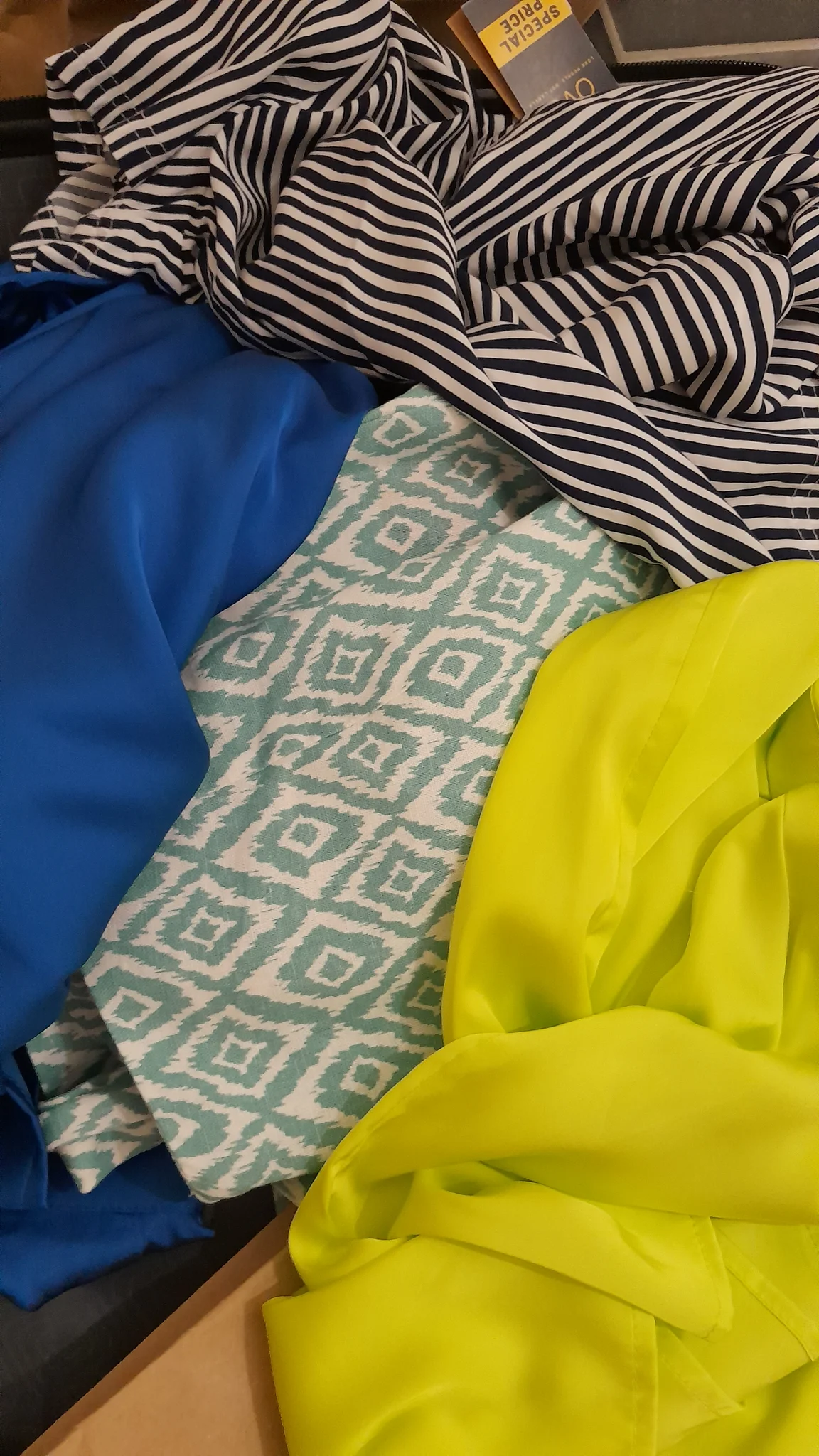 Une pile de tissus de différentes couleurs: bleu électrique, jaune fluo, vert menthe-à-l'eau à motifs losanges et rayures noires et blanches. Une pile de tissus de différentes couleurs: bleu électrique, jaune fluo, vert menthe-à-l'eau à motifs losanges et rayures noires et blanches.